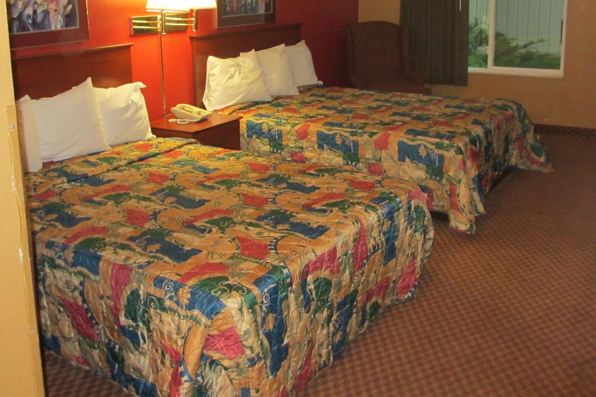 Une chambre d’hôtel avec deux lits, une table de chevet, une lampe et une chaise.