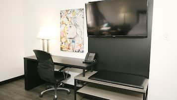 Une chambre d’hôtel équipée d’un bureau, d’une chaise, d’une télévision, d’œuvres d’art et d’une lampe.