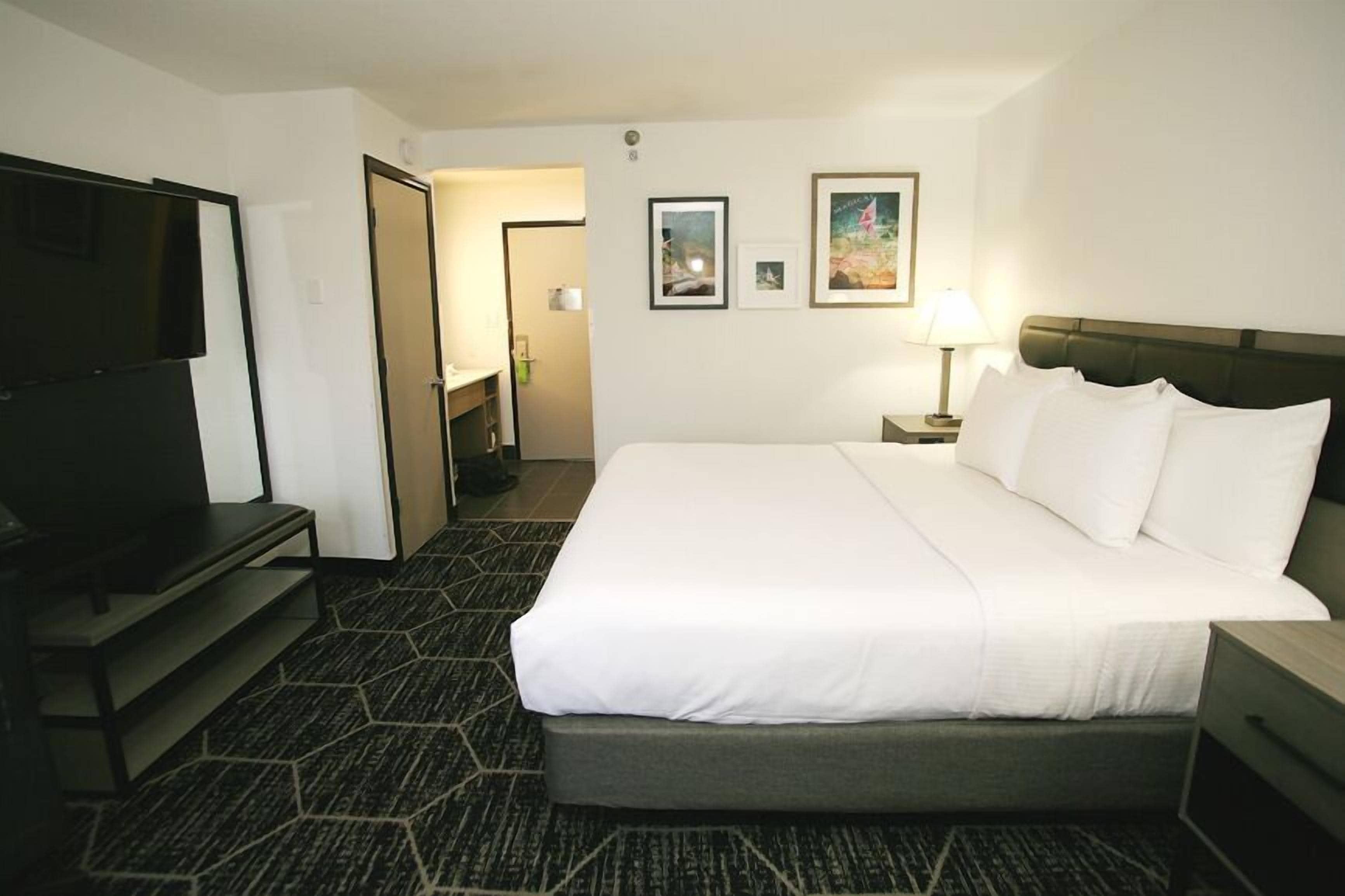Een hotelkamer met een groot bed, een flatscreen televisie, een bureau en een stoel.