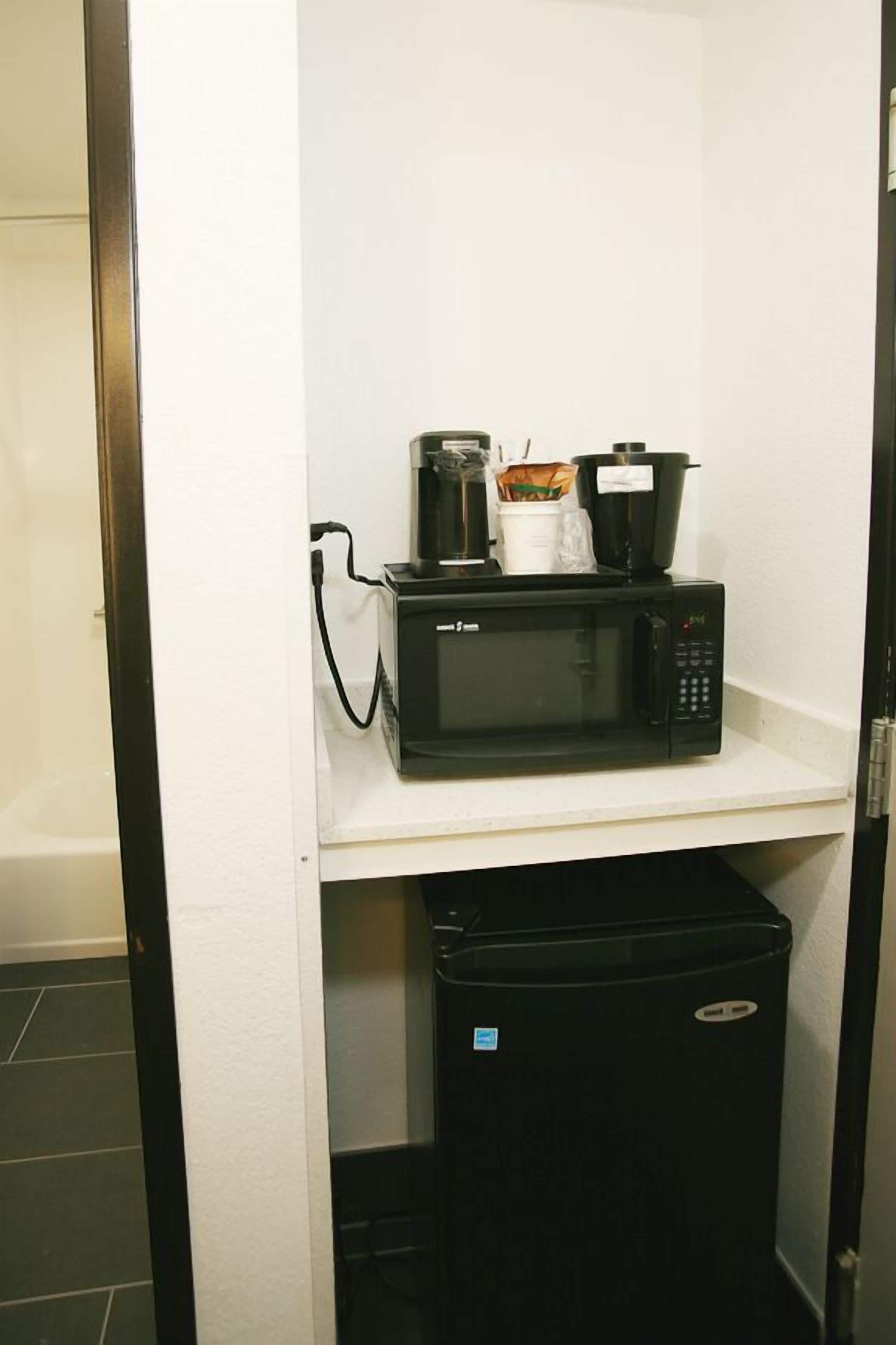 Une petite cuisine équipée d’un four à micro-ondes, d’une machine à café et d’un petit réfrigérateur.