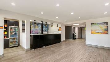 A modern reception area with a counter, a refrigerator stocked with beverages, and a colorful abstract painting on the wall.