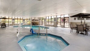 En indendørs swimmingpool med glasvægge, en redningsbøje og en badestige.