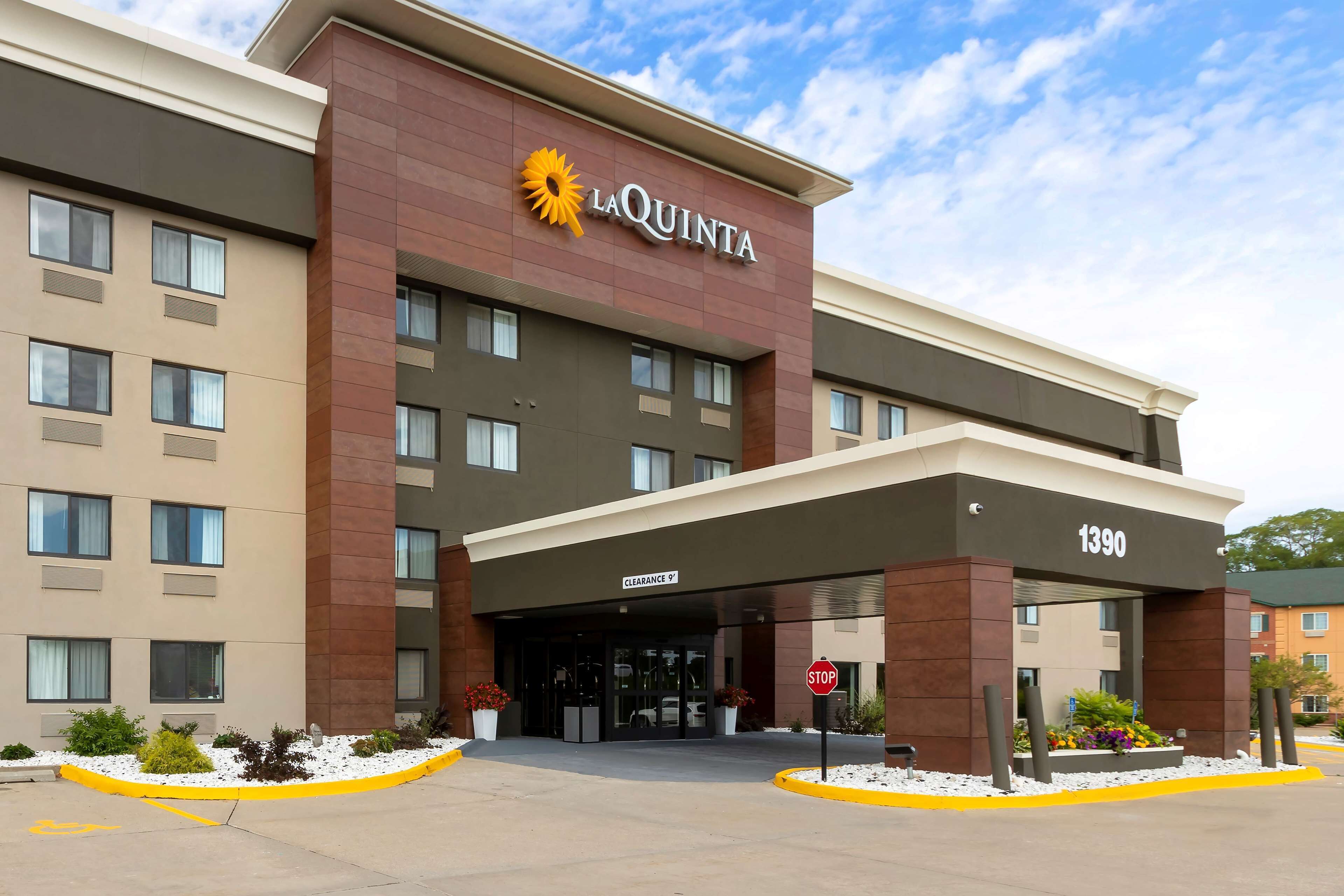 Hotel La Quinta con una fachada moderna, una entrada despejada y una señal de stop al frente.