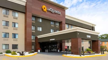 Hotel La Quinta con una fachada moderna, una entrada despejada y una señal de stop al frente.