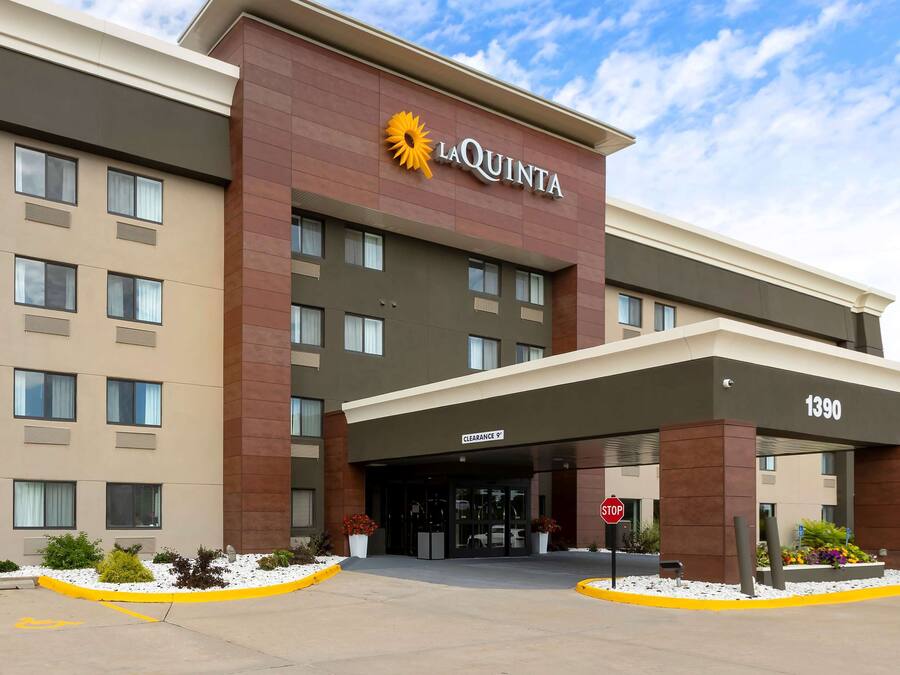 Hotel La Quinta con una fachada moderna, una entrada despejada y una señal de stop al frente.