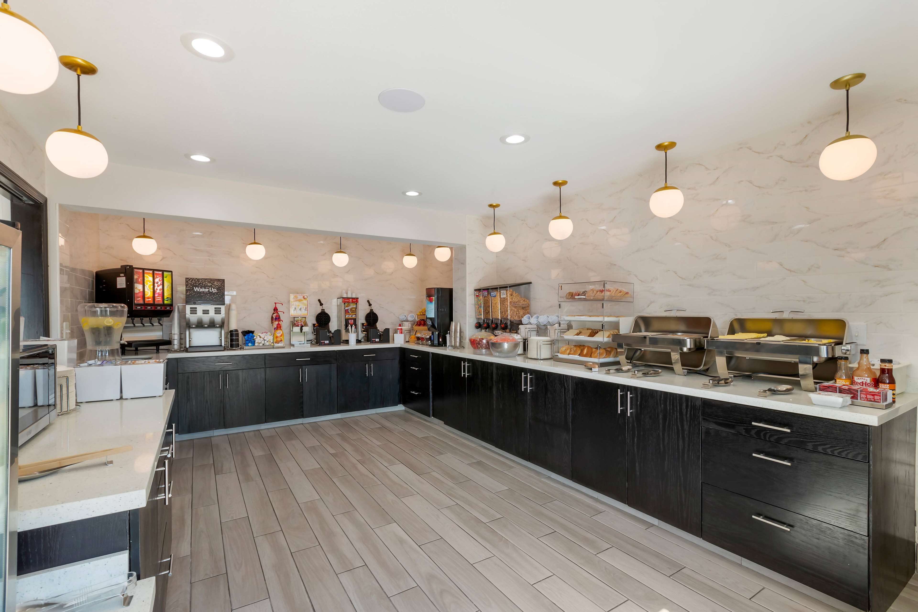 A modern kitchen with dark cabinets, a marble backsplash, and multiple cooking stations.