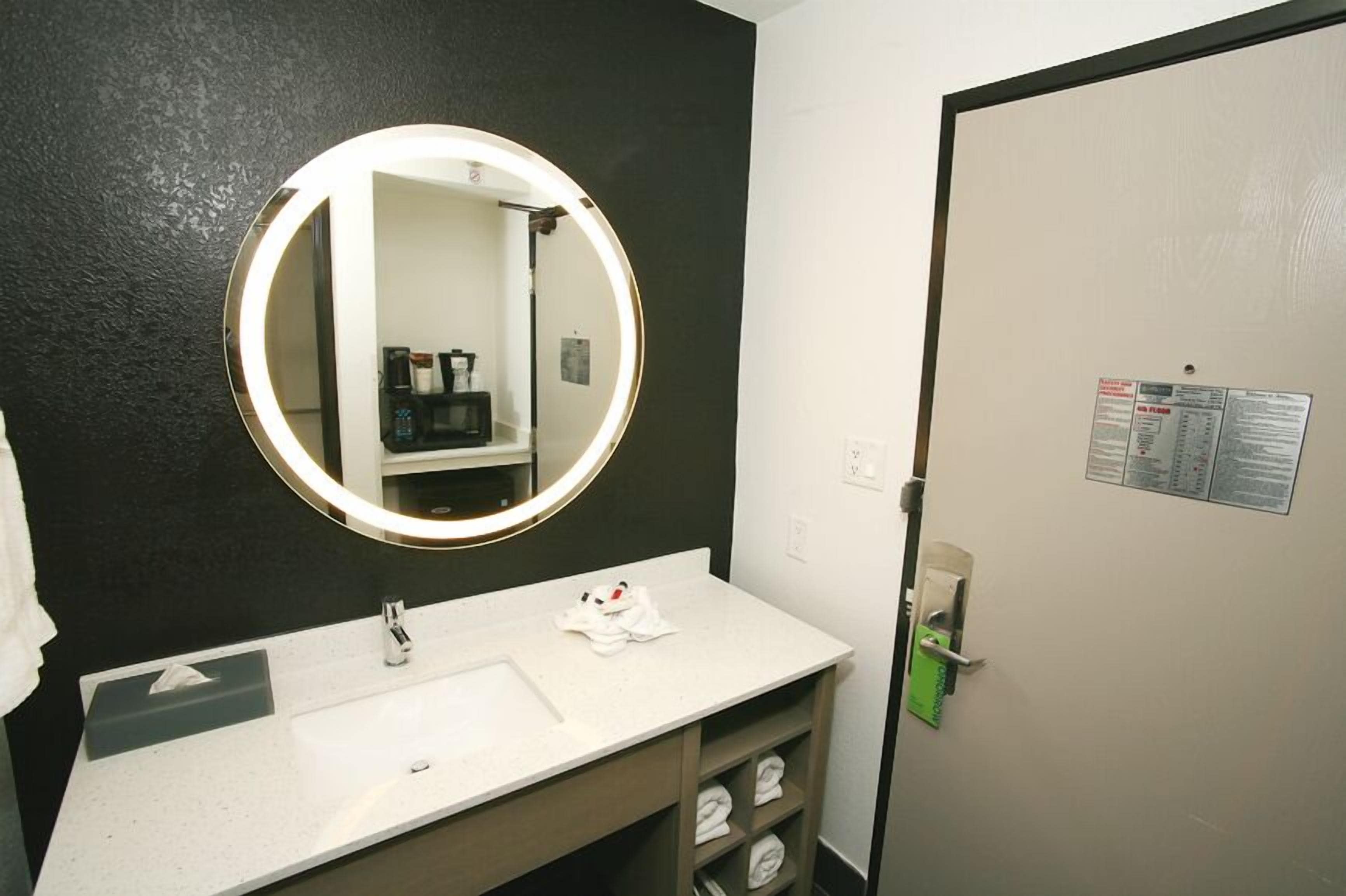 A bathroom with a round mirror, white sink, and a towel rack.