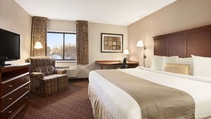 Une chambre d’hôtel avec un grand lit, une télévision, un bureau et une chaise.