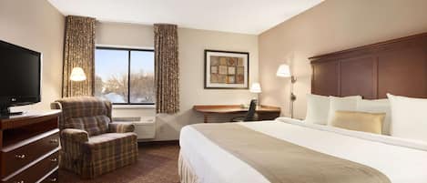 A hotel room with a large bed, a television, a desk, and a chair.