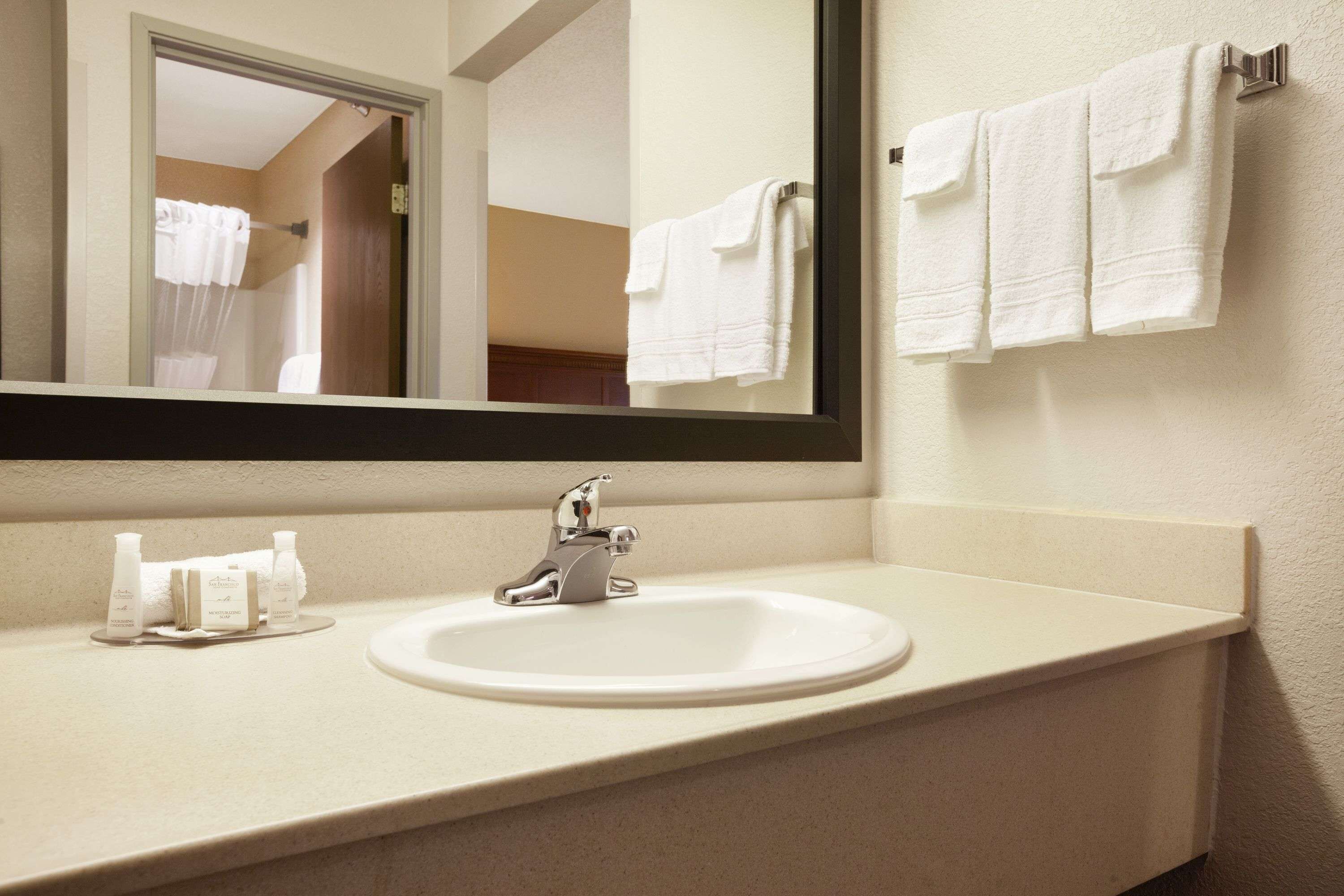 A bathroom with a sink, mirror, and towels.