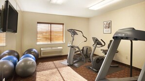 Une salle de remise en forme équipée de matériel d’exercice, notamment un tapis de course, un vélo elliptique et des ballons d’exercice.