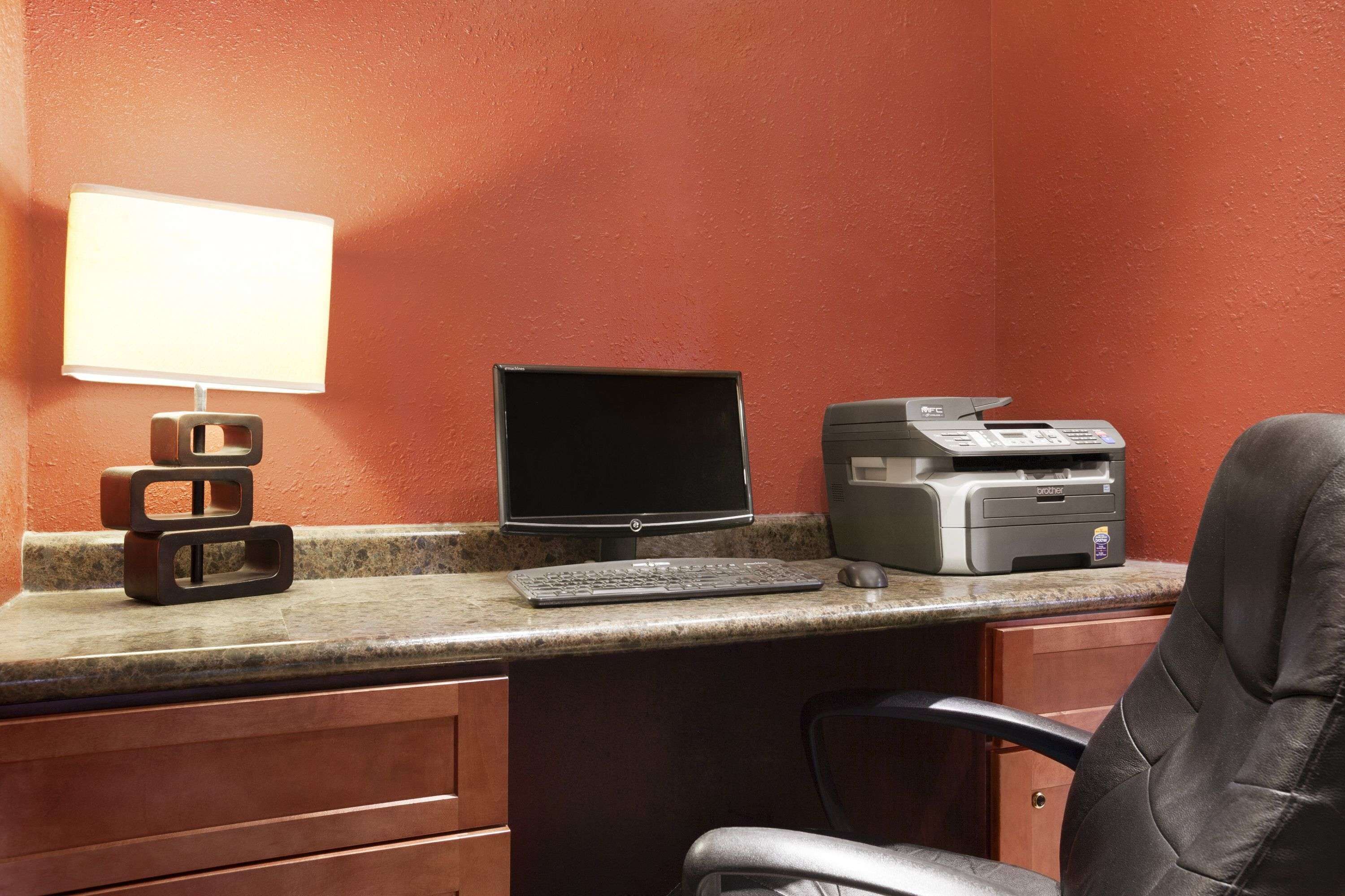A workspace with a desktop computer, a printer, and a lamp on a counter.