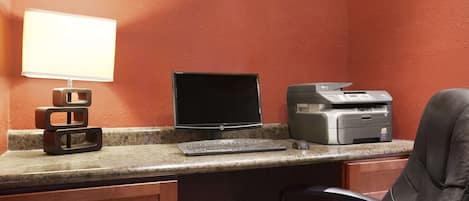 A workspace with a desktop computer, a printer, and a lamp on a counter.