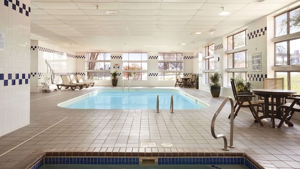 Une piscine intérieure avec un sol carrelé, des chaises longues et un espace équipé d’un jacuzzi.