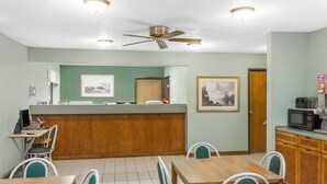 Ein Restaurant mit Holztresen, grünen Stühlen, einem Deckenventilator und gerahmten Bildern an den Wänden.