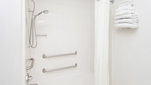 Ein Badezimmer mit Dusche, Haltegriffen und einem Handtuchhalter.