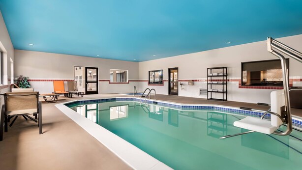 Une piscine avec un plafond bleu, un transat et une petite table avec des chaises.