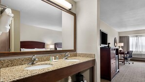 Une salle de bain d’hôtel avec deux lavabos, un grand miroir et une coiffeuse équipée d’un téléviseur.