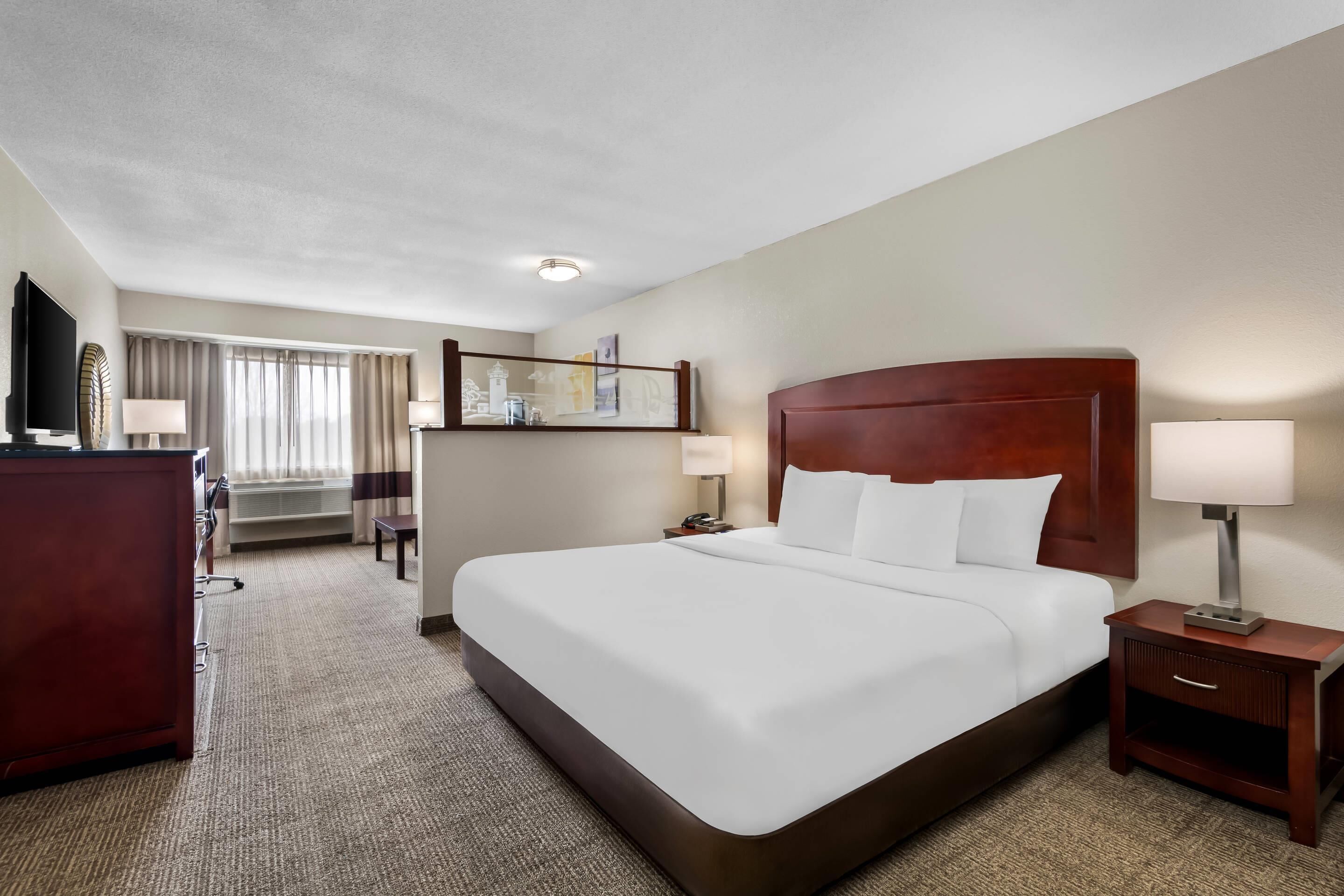 A hotel room with a large bed, a desk, a TV, and a bathroom.