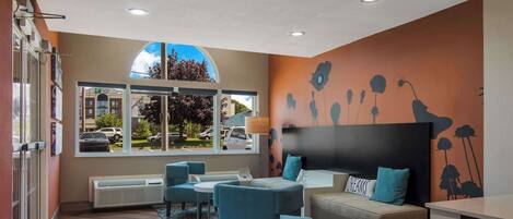 A modern hotel lobby with a large window, seating area, and a decorative wall.
