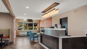 A reception area with a modern design, featuring a reception desk, seating area with chairs, and a view of the outdoors through large windows. - Sleep Inn Erie near Sports Center (Erie)