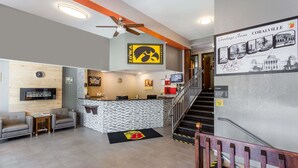 A hotel lobby with a reception desk, seating area, and a staircase. - Super 8 by Wyndham Iowa City/Coralville (Coralville)