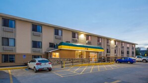 A multi-story hotel with a green awning, parking spaces, and a handicap-accessible entrance. - Super 8 by Wyndham Iowa City/Coralville (Coralville)