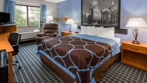 A hotel room with a bed, a desk, a chair, a television, and a large framed picture on the wall. - Super 8 by Wyndham Iowa City/Coralville (Coralville)