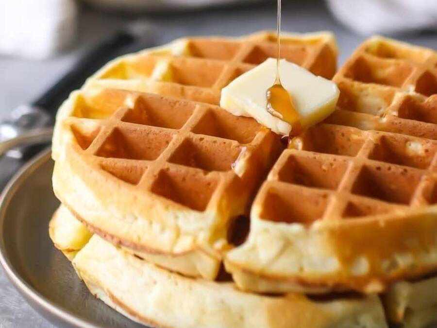A waffle with syrup being poured on it.