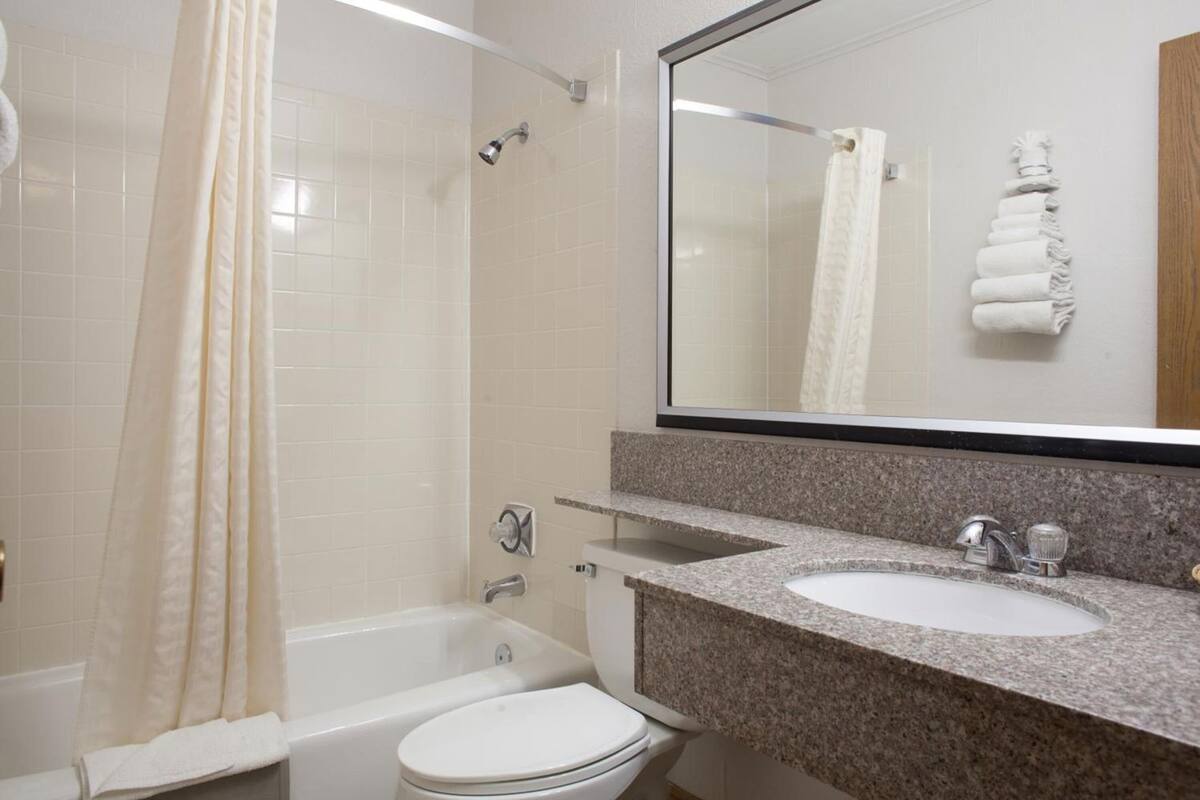 A bathroom with a bathtub, toilet, sink, and a shower curtain.