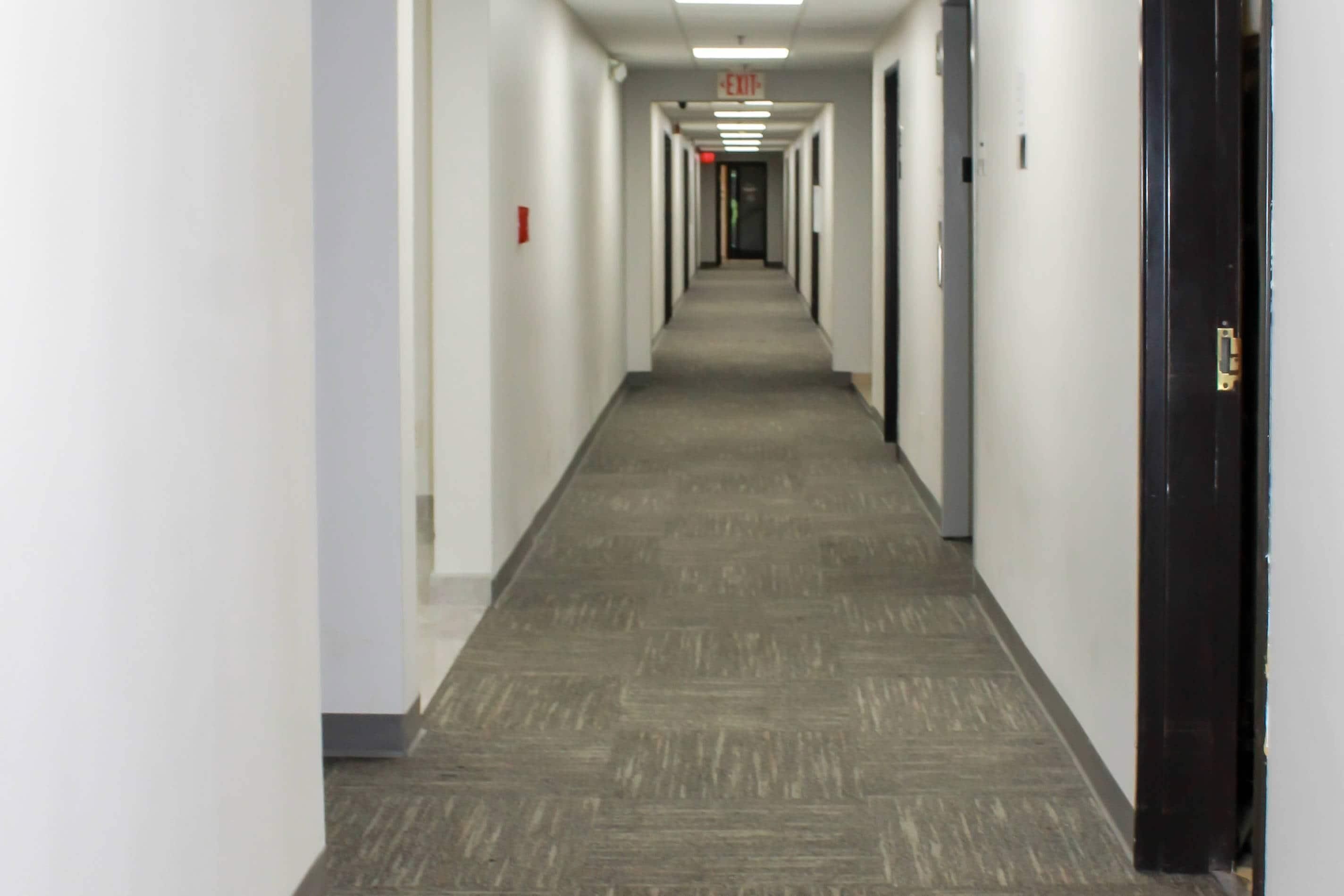 A long, narrow hallway with carpeted floors and white walls.