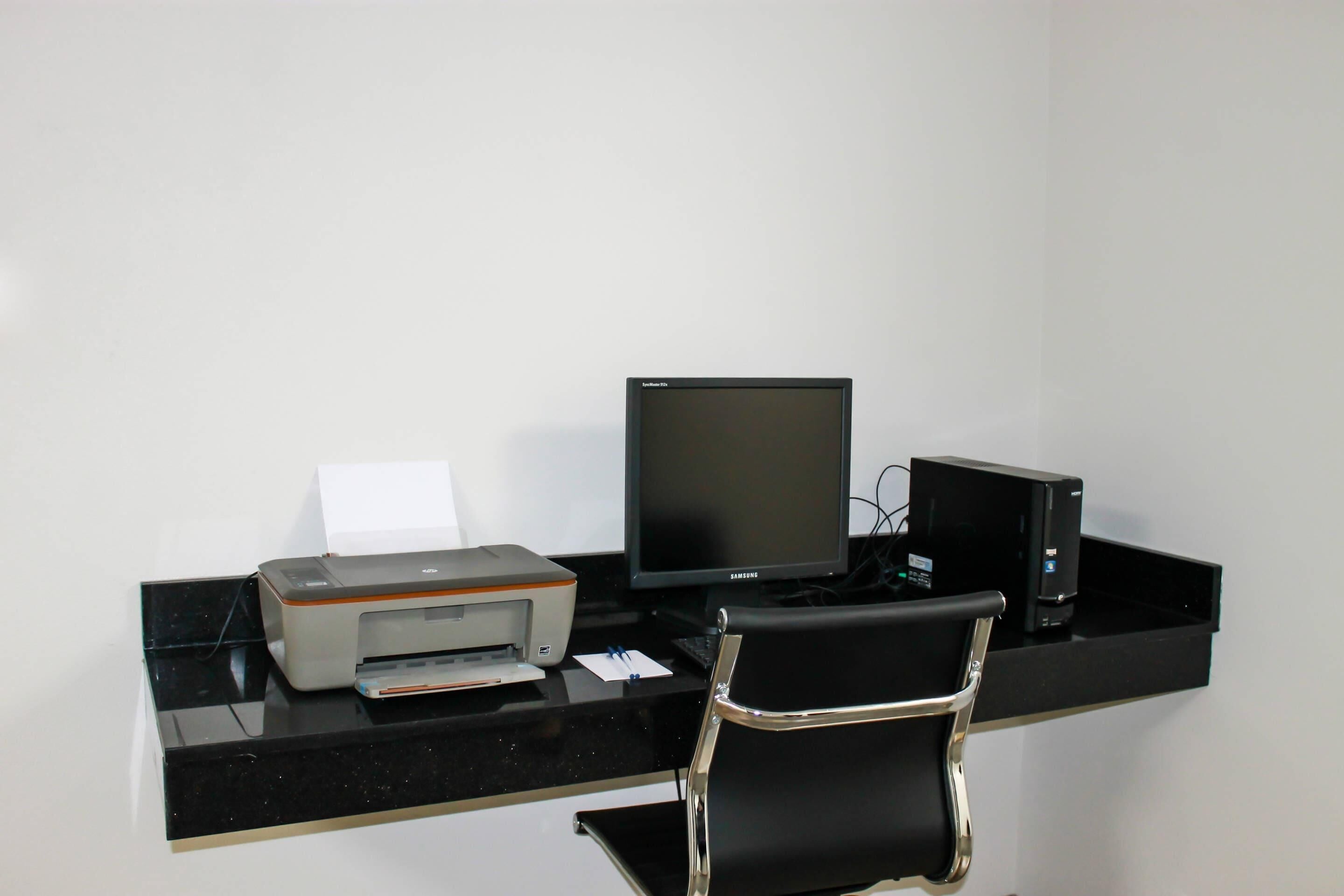 Un escritorio moderno con una computadora, impresora y silla.
