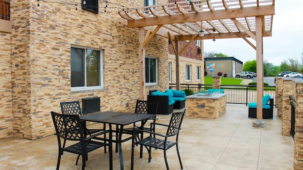 An outdoor patio with stone walls, a pergola, and outdoor seating. - Clarion Pointe Bettendorf - Quad Cities (Bettendorf)