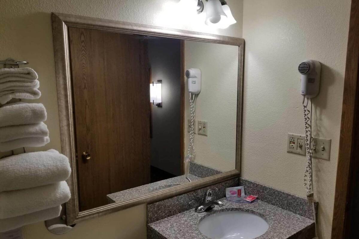 A bathroom with a sink, a mirror, a towel rack, and a hair dryer.