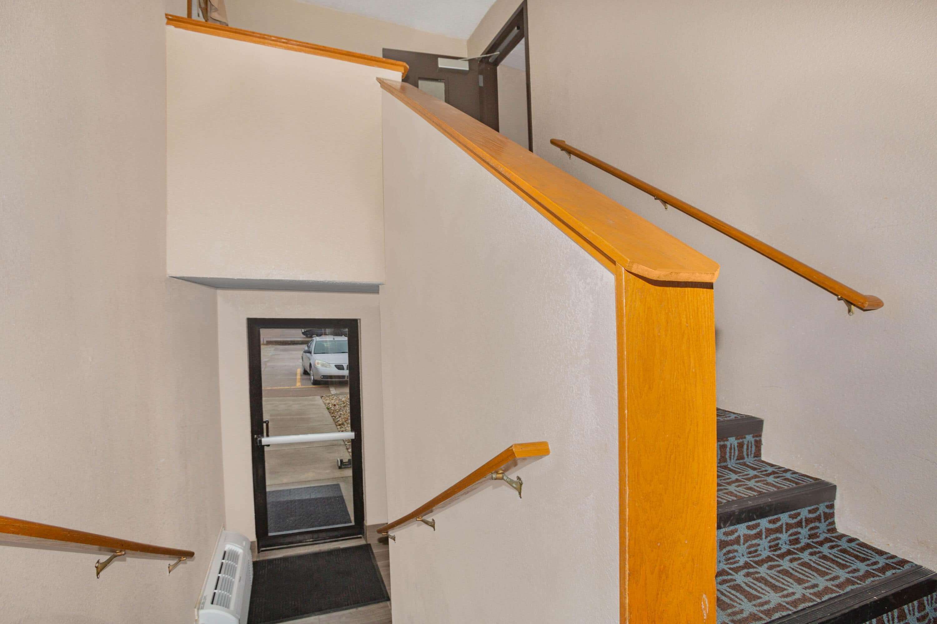 Una escalera con barandillas de madera y un rellano alfombrado.