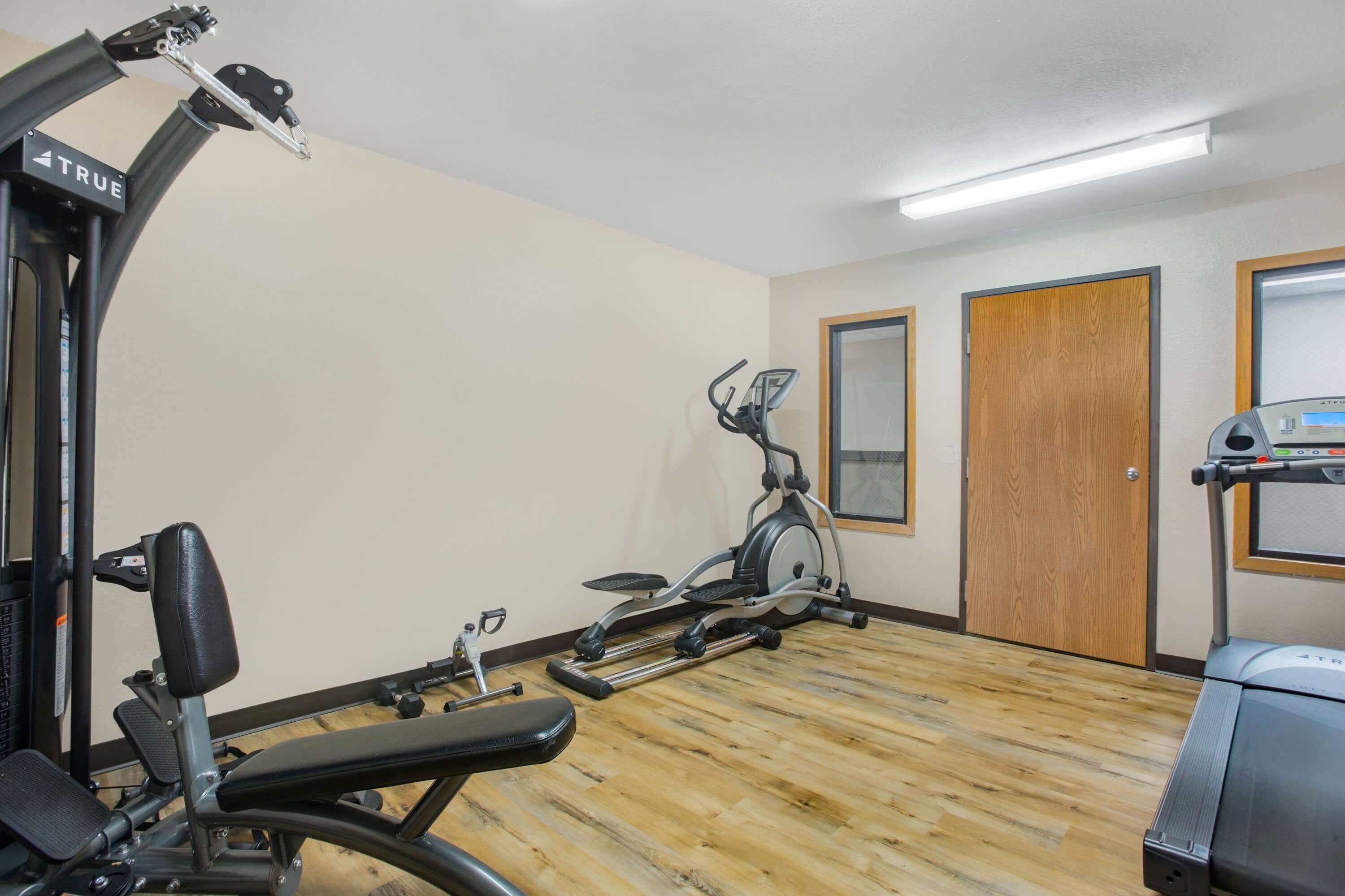 Un gimnasio con equipo de ejercicio, incluyendo una caminadora, bicicleta estática y máquina de pesas.