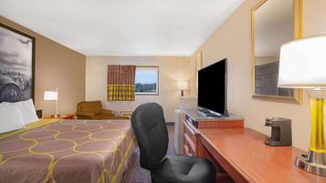 Quarto de hotel com cama, escrivaninha, cadeira, televisão, abajur e janela com cortinas.