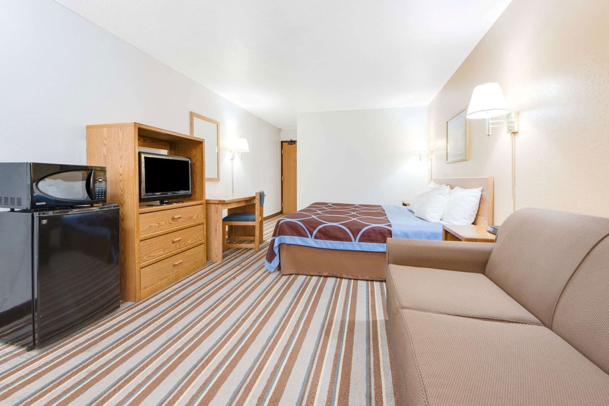 Ein Hotelzimmer mit einem Bett, einem Sofa, einem Schreibtisch mit Stuhl, einer Mikrowelle und einem Kühlschrank.