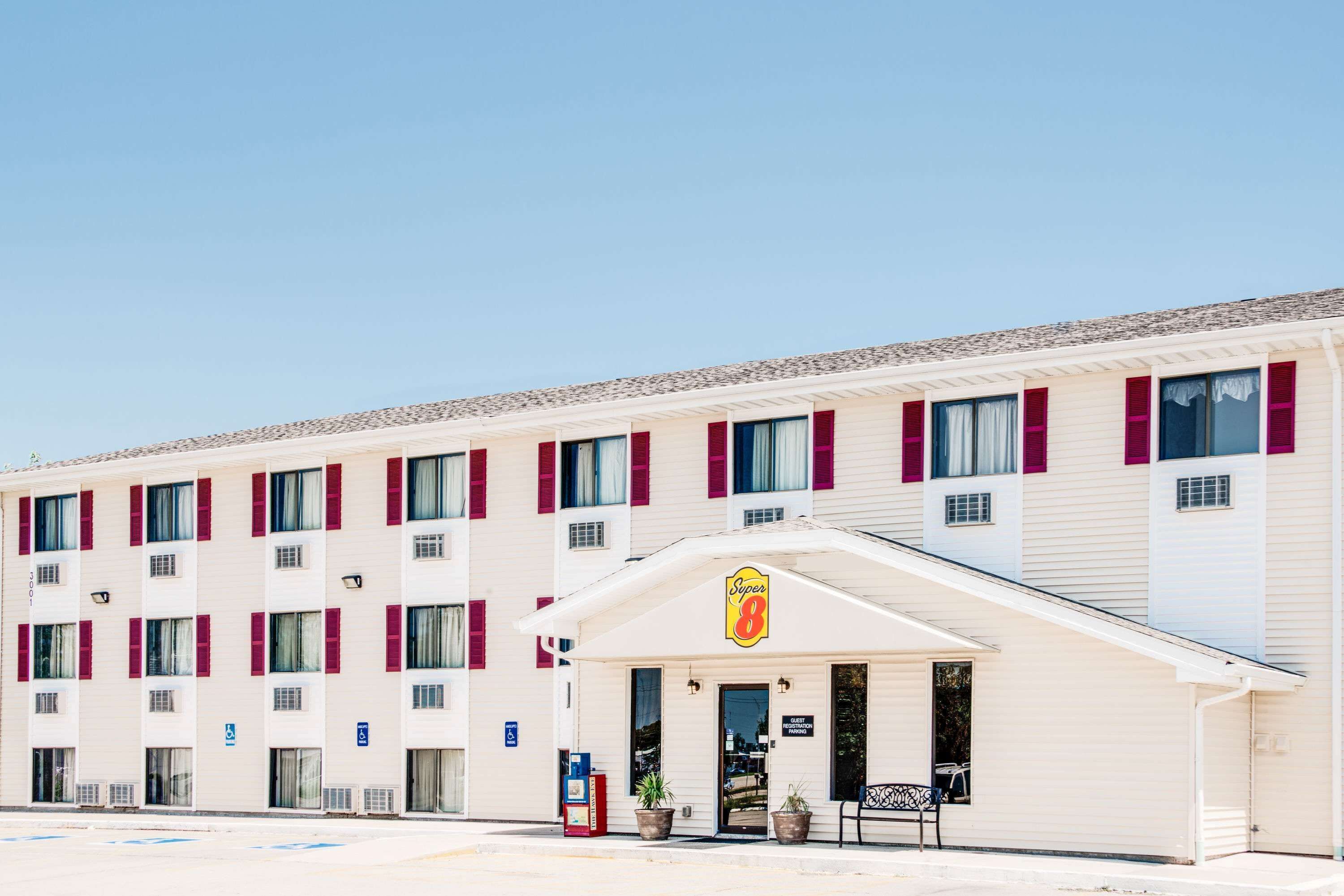 Un hôtel à la façade blanche, aux volets rouges et arborant le logo Super 8.