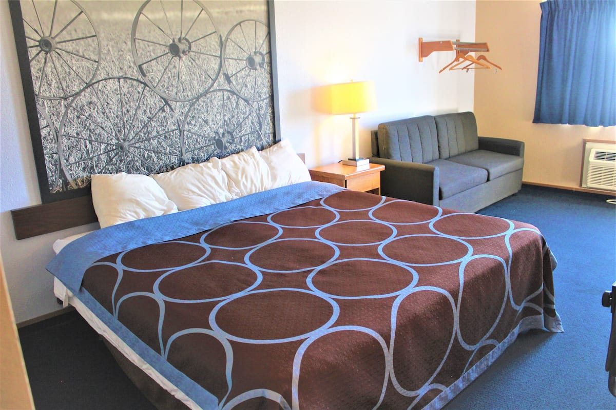 Ein Hotelzimmer mit einem großen Bett, einer Couch, einer Lampe und einem Wandbild.