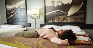 A hotel room with a bed, a nightstand with a lamp, and two large framed pictures on the wall. - Super 8 by Wyndham Burlington (Burlington)
