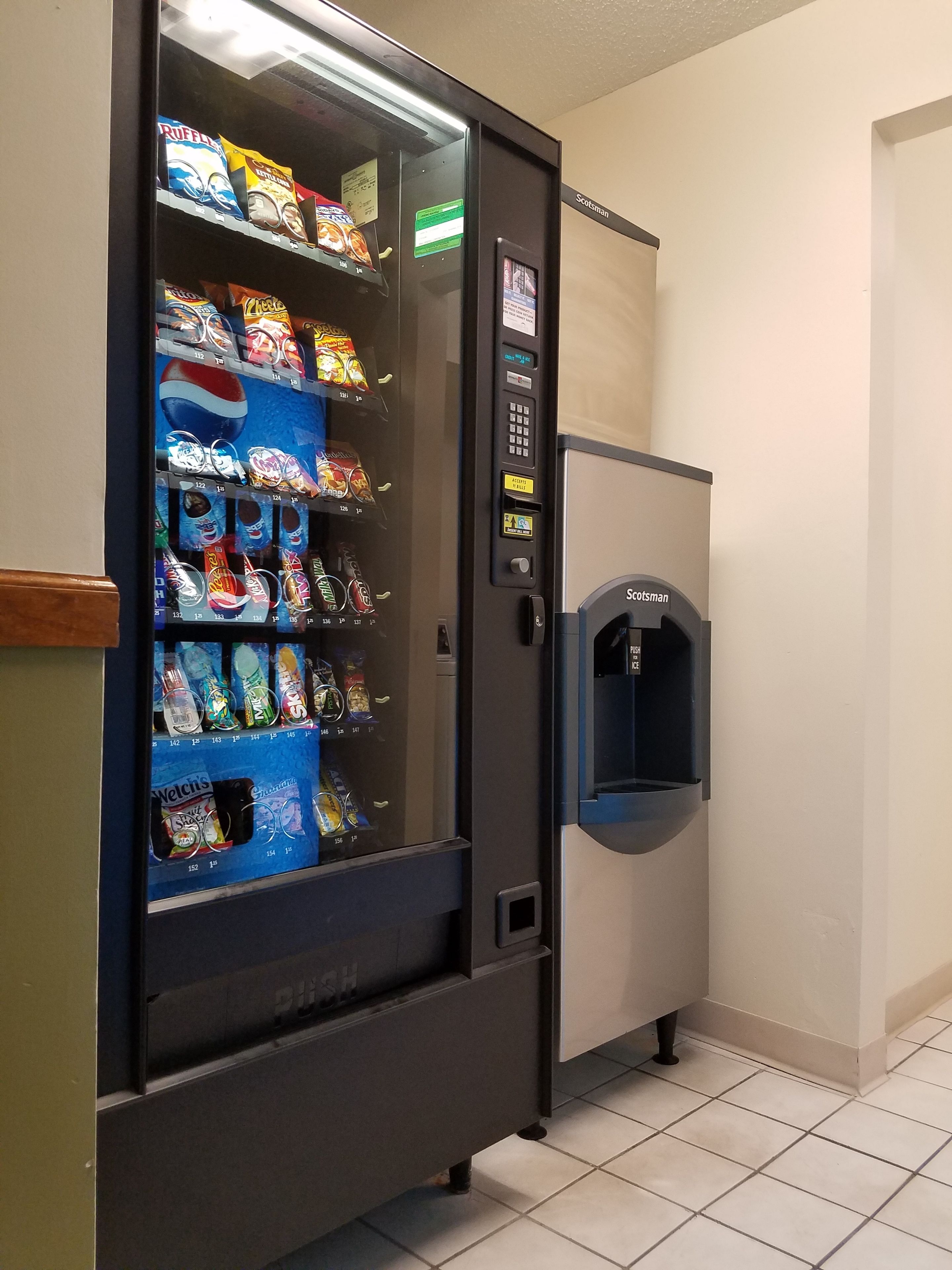 A vending machine with snacks and drinks, a water dispenser, and a sign indicating 'Scotsman'.