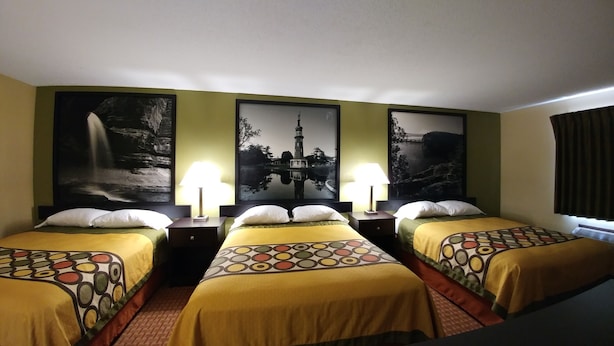 Een hotelkamer met twee eenpersoonsbedden, elk voorzien van een beddengoed met een patroon en witte kussens. Er zijn twee nachtkastjes met lampen. De muren zijn versierd met grote zwart-wit landschapsprenten.