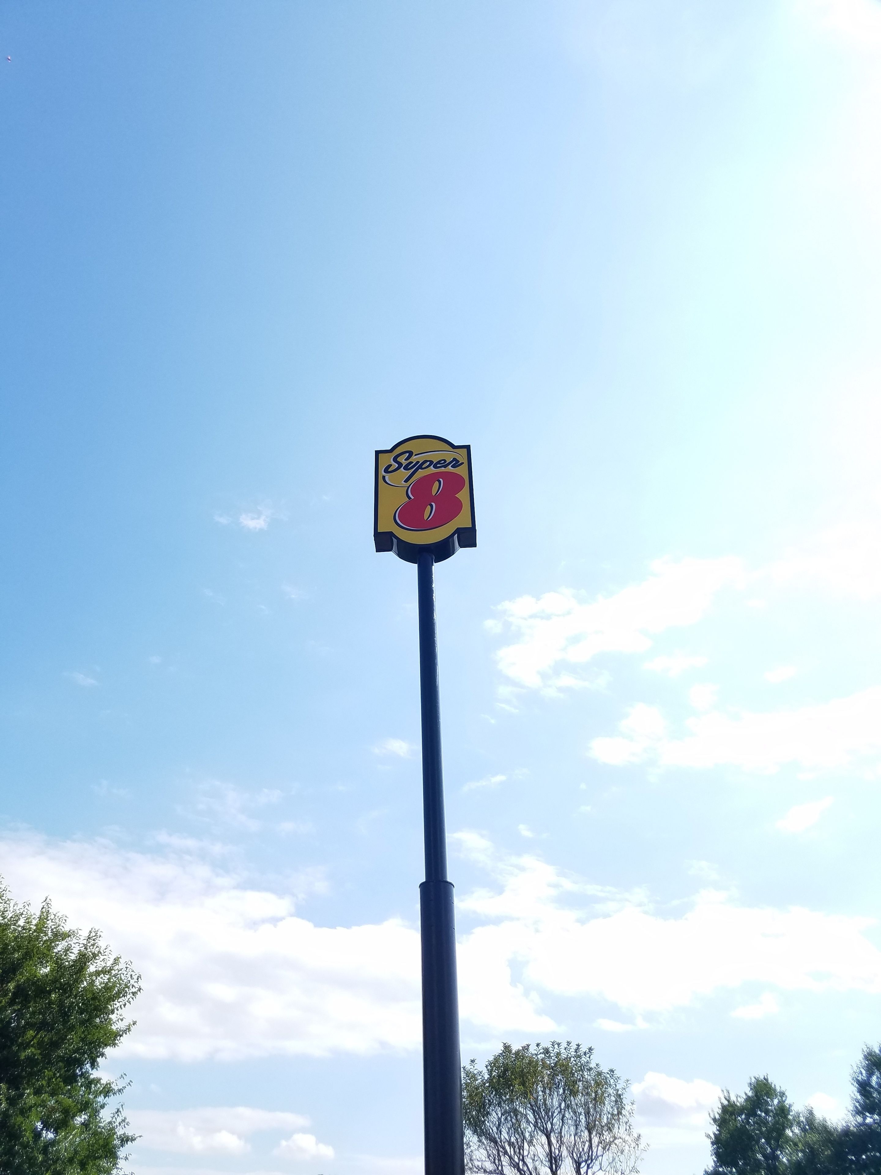 A tall pole with a sign that reads "Super 8" against a clear blue sky.