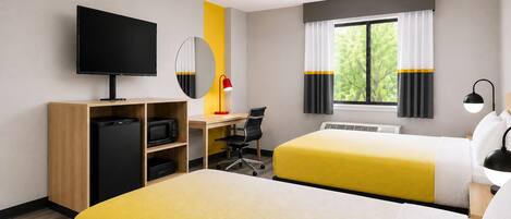 A hotel room with two beds, a desk, a television, a microwave, and a window with curtains.