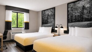 A hotel room with two beds, a desk, a chair, a window with curtains, and two wall-mounted lamps. - Super 8 by Wyndham Champaign (Champaign)