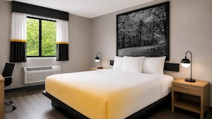 A modern hotel room with a large bed, two bedside tables with lamps, a window with curtains, a radiator, and a wall-mounted artwork. - Super 8 by Wyndham Champaign (Champaign)