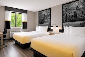 A hotel room with two beds, a desk, a chair, an air conditioning unit, and two wall-mounted lamps. - Super 8 by Wyndham Champaign (Champaign)