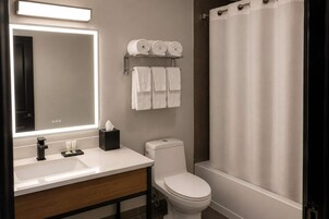 Un baño moderno con un lavamanos blanco, un inodoro y una zona de ducha.