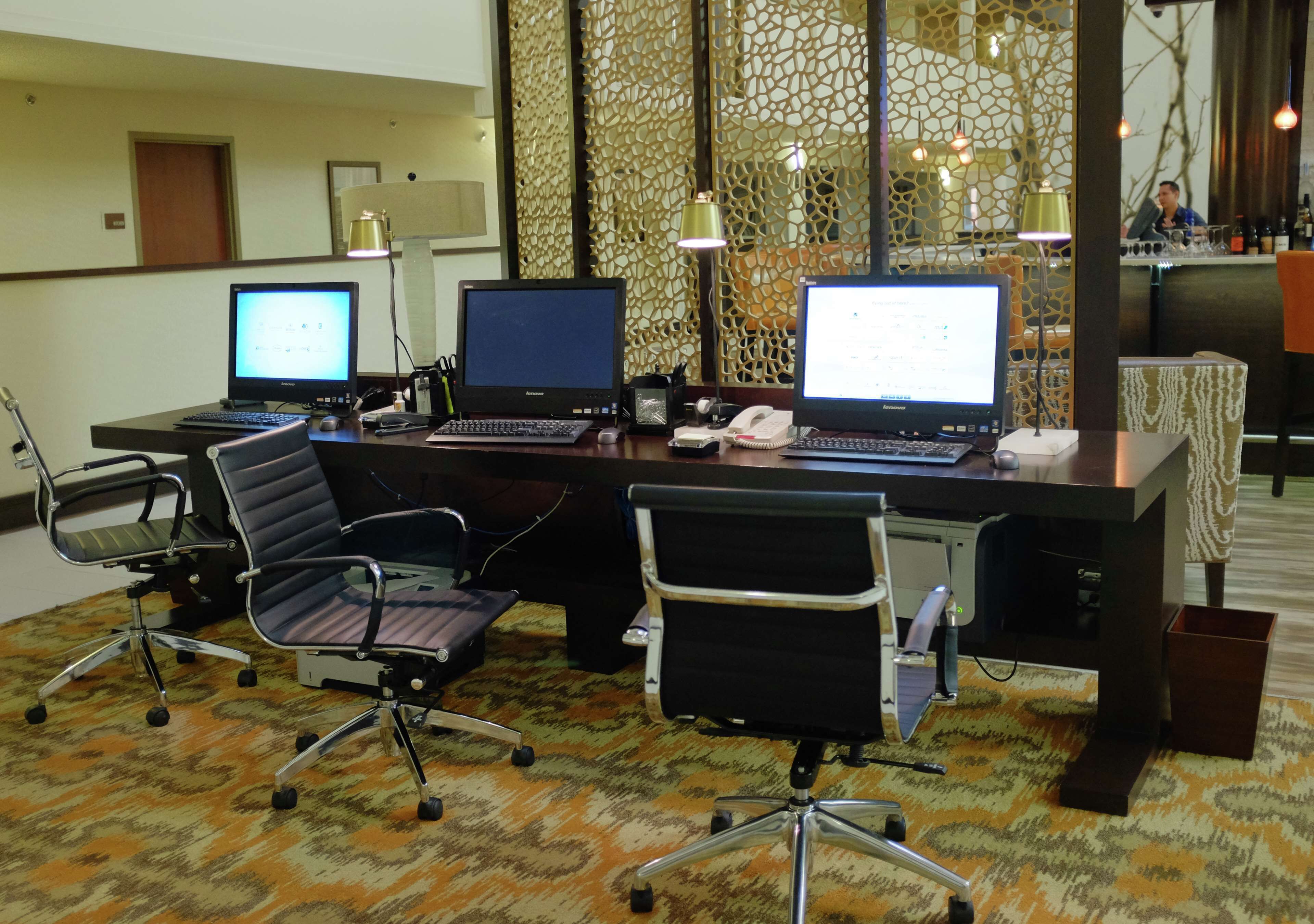 Une salle de conférence équipée de trois bureaux, chacun doté d’un ordinateur, de deux chaises de bureau et d’un tapis à motifs.